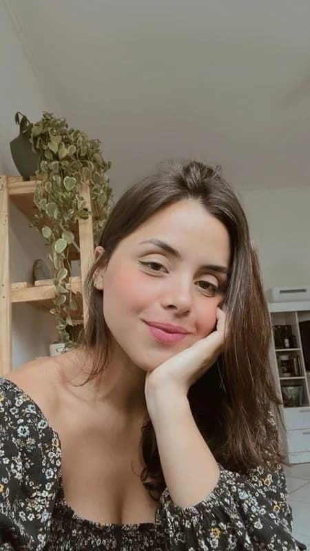 Brenda Nicolau, a bordadeira da nicolines, sorrindo com a mão no rosto